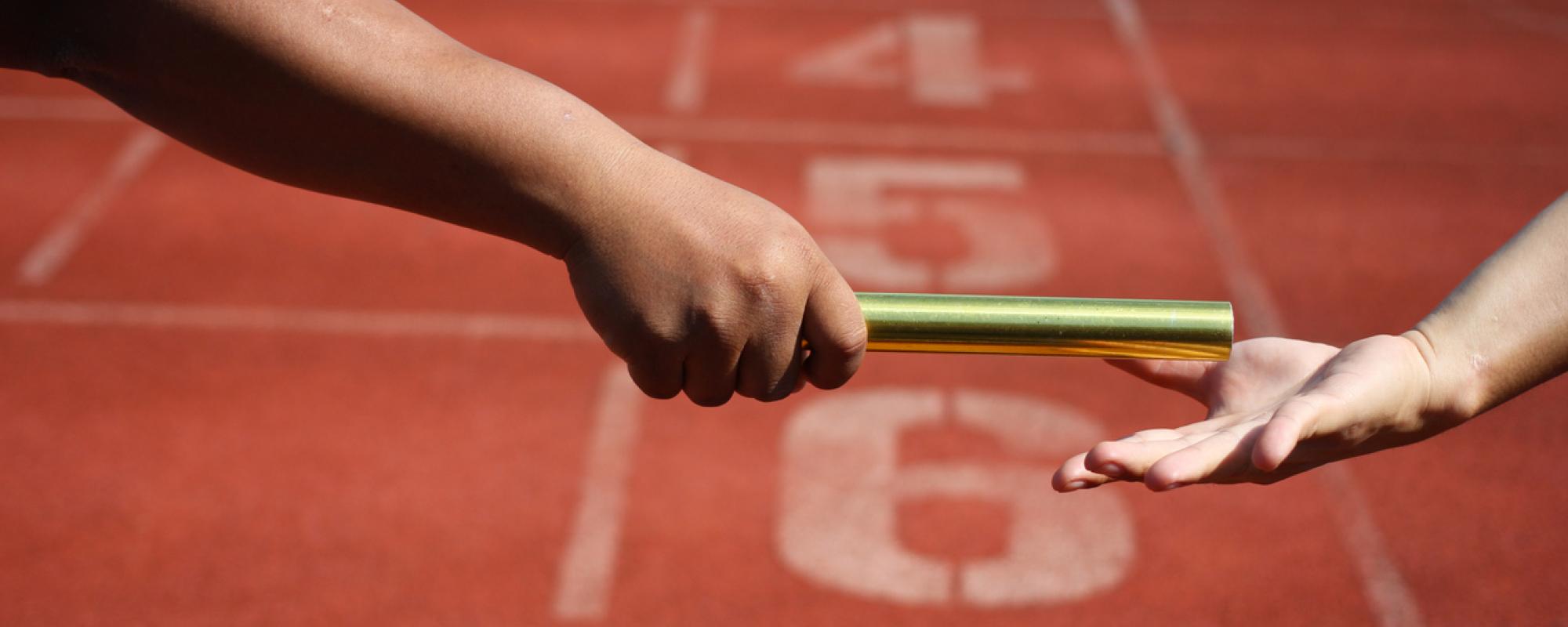 Relay runners handing over baton - close up of hands